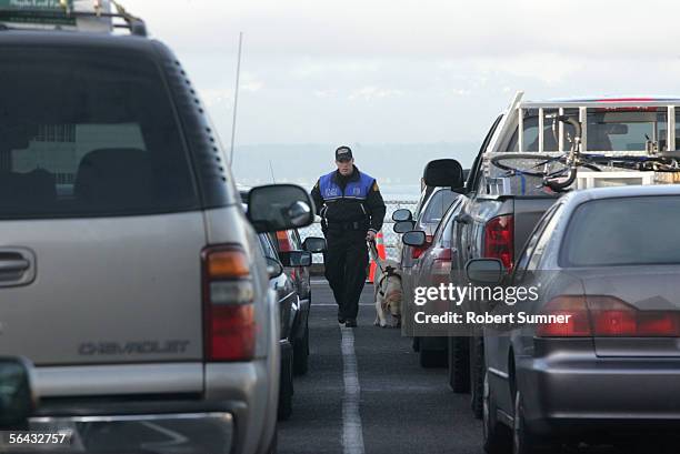Matt Chatterton, of the Washington State Patrol, with his dog, checks cars waiting to board a Washington State Ferry to Bainbridge Island December...
