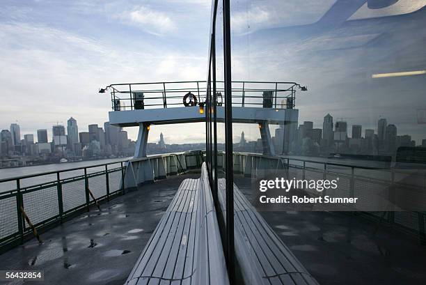 The Seattle skyline is reflected in the window of a Washington State Ferry as it departs Seattle Pier 52 for Bainbridge Island, Washington December...