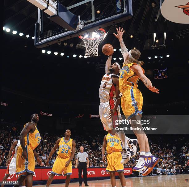 Baron Davis of the Golden State Warriors takes the ball to the basket against Chris Andersen of the New Orleans/Oklahoma City Hornets during a game...