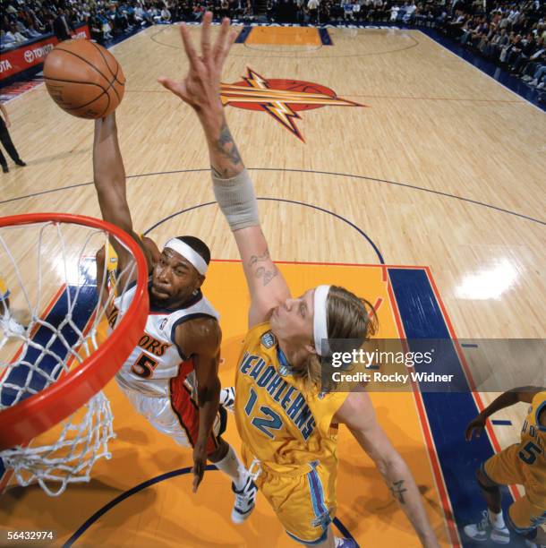 Baron Davis of the Golden State Warriors takes the ball to the basket against Chris Andersen of the New Orleans/Oklahoma City Hornets during a game...