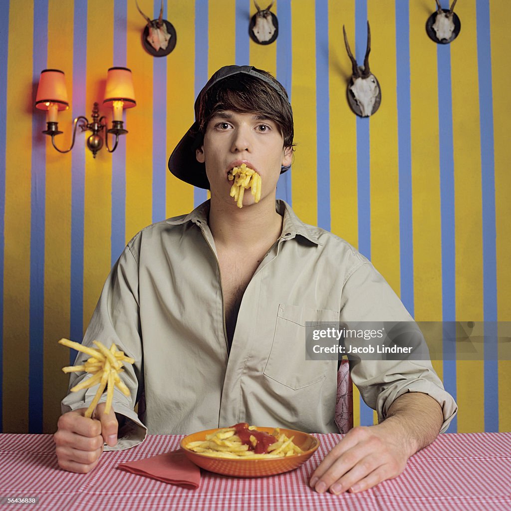 Young man eating French fries