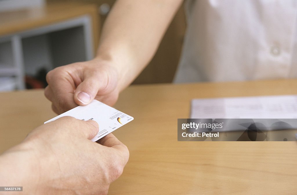 Man handing out health insurance card, midsection