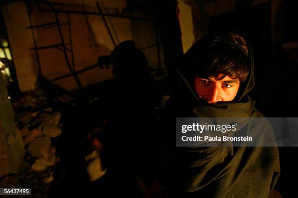 Abdul Momen tries to keep warm while he waits for his dinner in a makeshift outdoor restaurant December 15, 2005 in the devastated town of Balakot,...