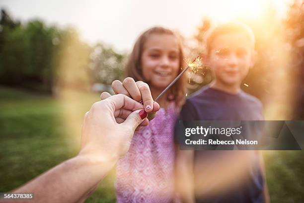 mother's hand holding out sparkler to kids - illinois family stock pictures, royalty-free photos & images