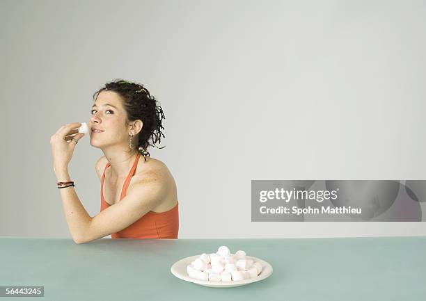 young woman eating marshmallows - marsh mallows stock pictures, royalty-free photos & images