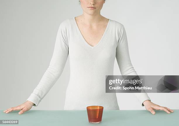 young woman standing with glass in front of her on table, partial view - v ausschnitt stock-fotos und bilder