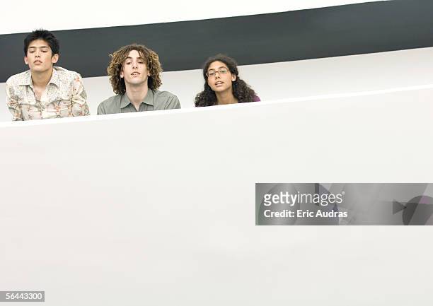 three young people looking over edge of balcony - ergens overheen kijken stockfoto's en -beelden
