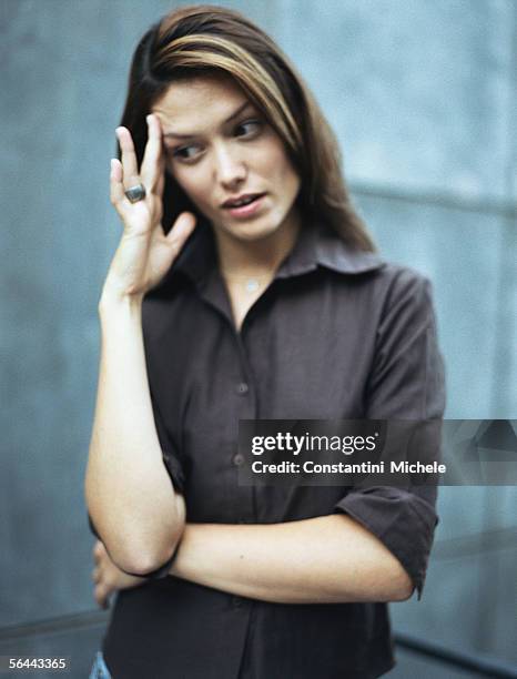 woman standing with one arm across body, holding head and looking away - awkward bildbanksfoton och bilder