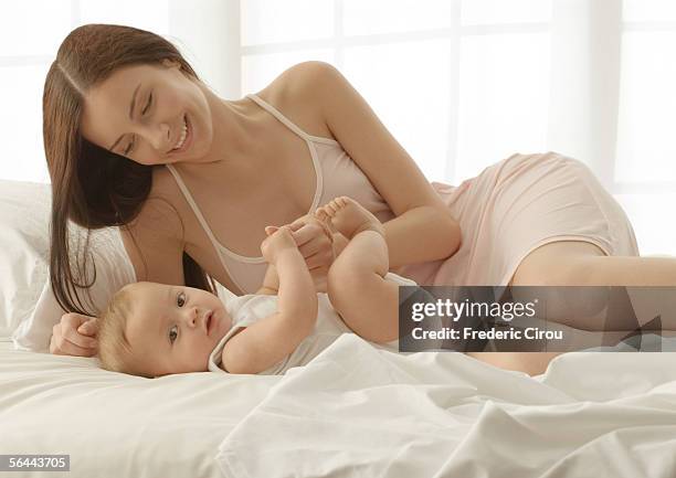 baby and mother on bed - allongé sur le dos photos et images de collection