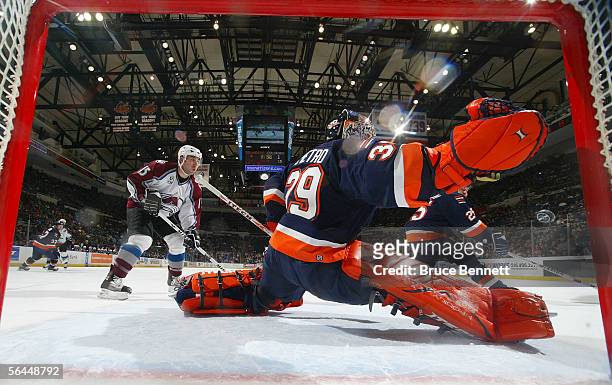 Rick DiPietro of the New York Islanders saves the puck in front of Andrew Brunette of the Colorado Avalanche at the Nassau Coliseum on December 17,...