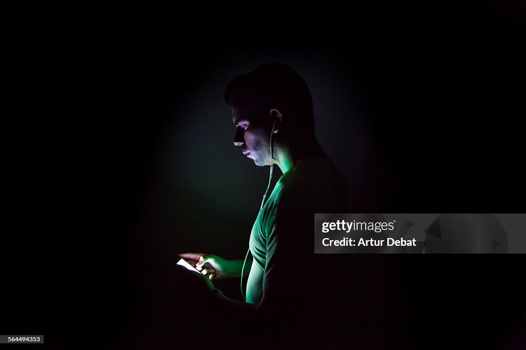 Runner checking his smartphone music at night.