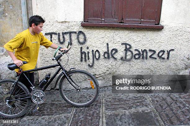 Un nino camina junto a un grafitti contra el candidato presidencial Jorge "Tuto" Quiroga en el centro de La Paz, el 18 de diciembre de 2005 durante...