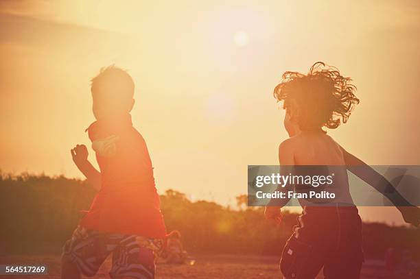 two young boys running on the beach at sunset. - el mirage stock-fotos und bilder