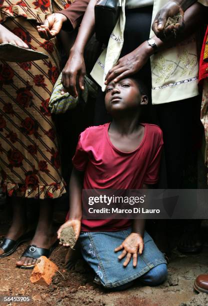 Year-old Ruth Nakabonge throws earth over her fathers coffic during his funeral on December 14, 2005 in Bbambula, a village 50 km North of the...