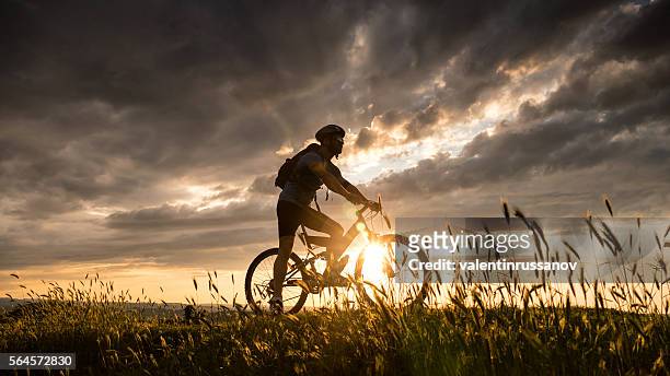 silhouette of young man cycling on top of the hill - bike headset stockfoto's en -beelden