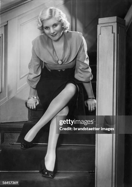 Stockings in fashion: A blonde girl sitting on the stairs of Yva's studio in Berlin. Photography by Yva. Around 1935. [Strumpfmode: Blondes Maedchen...
