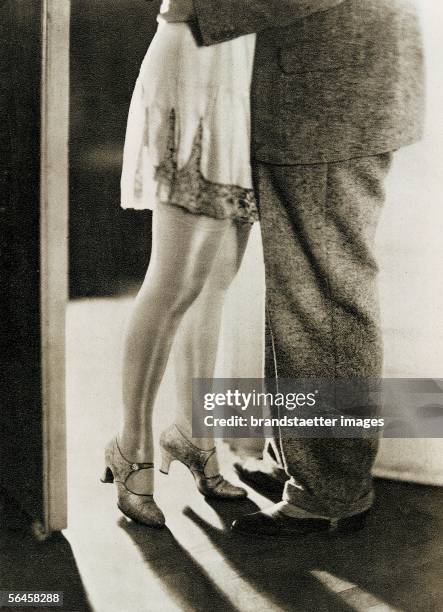 Woman in her negligee and stockings and man in his suit standing at the door. Photography by Erlanger v. Rosen., 1930. [Frau in Neglige und...