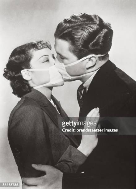 Film kiss with protective mask to prevent infection during a flu epidemic in Hollywood. Photography. 1937. [Filmprobe einer Kussszene mit...