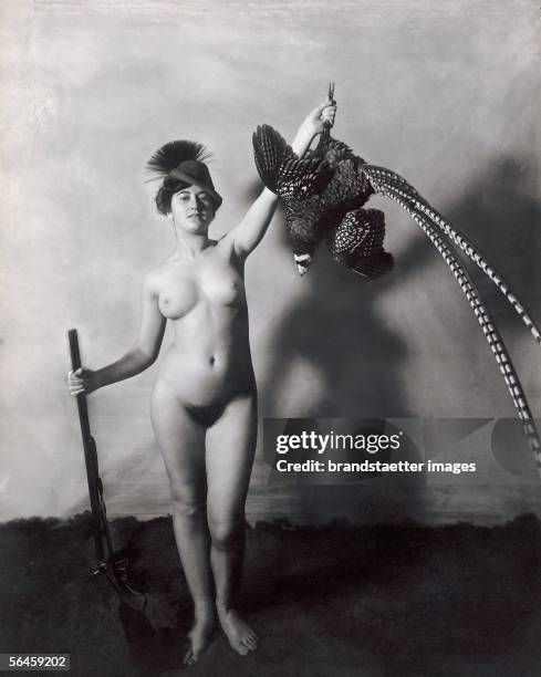 Nude with shotgun, pheasant and "Gamsbart"-hat. Photography.1906. [Nacktes Maedchen mit Gamsbart- Hut, Gewehr und hochgehaltenem Fasan. Photographie....