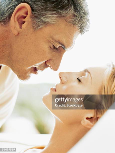 close-up of a mid adult man kissing a mid adult woman on a bed - casal de idade mediana - fotografias e filmes do acervo