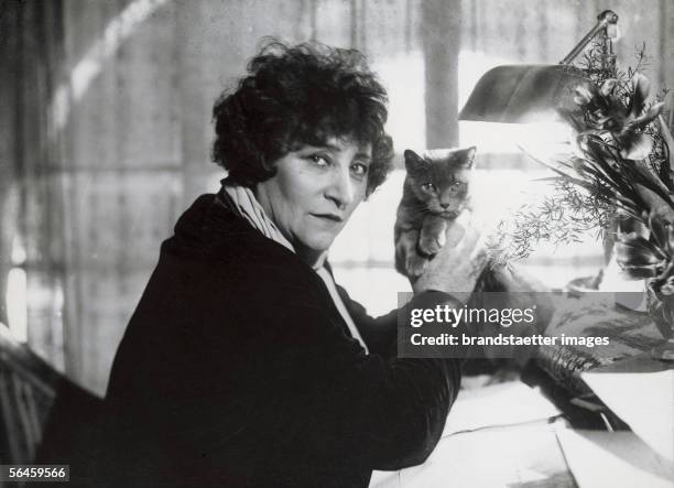 Sidonie Gabrielle Colette , French writer, with her cat at the desk. Paris. Photography. 1935. [Sidonie Gabrielle Colette , franzoesische...