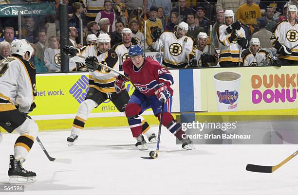 Center Arron Asham of the Montreal Canadiens carries the puck while being hooked by defenseman Jamie Rivers of the Boston Bruins during game 5 of the...