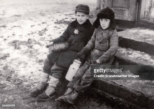 Holocaust: Two children in the snow covered Ghetto of Warsaw, one boy with Yellow Star on the coat and bowl, the other with milk can. Photography....