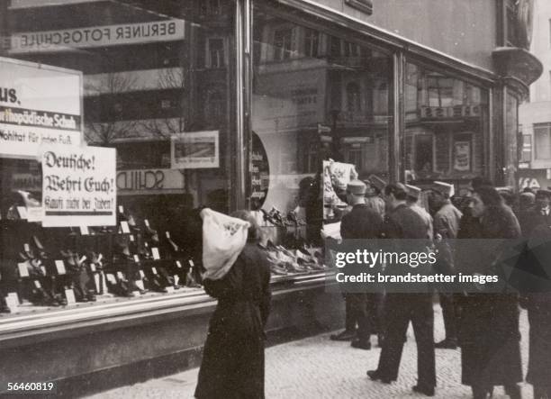 Nazi boycott against Jewish shops in Germany: SA members sticking anti-Semitic signboards on Jewish shops in Berlin. Photography. 1933. [Boykott der...