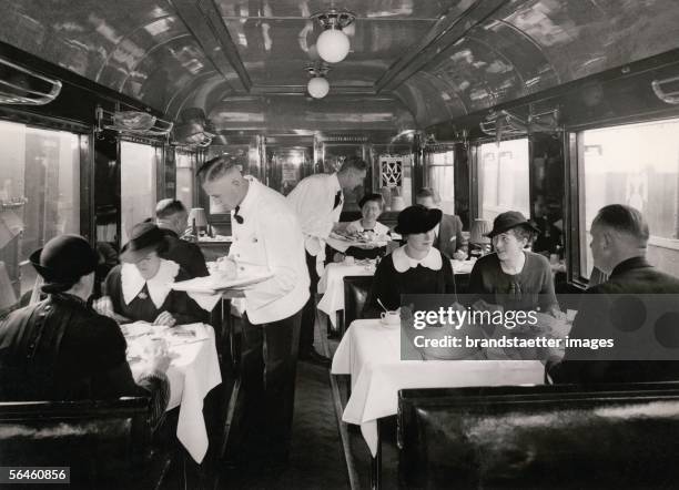 Mitropa" dining-car, Germany. Photography. Around 1935. [Blick in einen Mitropa-Speisewagen der Deutschen Bahn mit Gaesten und servierenden Kellnern...