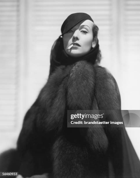 Hollywood actress Carole Lombard with velvet hat, fur coat and cigarette. Hollywood. Photography. About 1930. [Die Hollywood-Schauspielerin Carole...