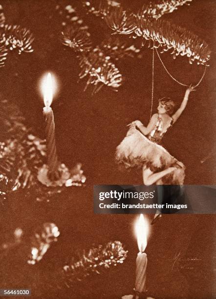 In the light of the Christmas candles. Dancer Bea Egervary": Girl hanging on a Christmas tree next to candles. Photomontage. 1929. ["Im Licht der...