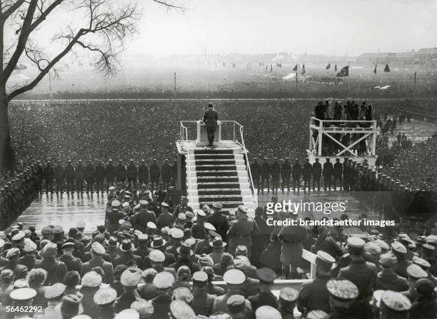 Adolf Hitler is taking a speech in front of a huge crowd at the national holiday at the Tempelhofer field. Berlin. Germany. Photography. 1.5.1933....