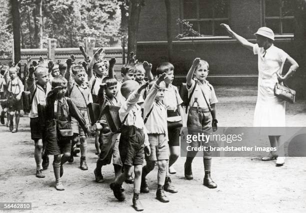 Teacher is seeing off her school children with the "Hitler Gruss" . Photography. Around 1933. [Eine Lehrerin verabschiedet ihre Schulkinder mit dem...