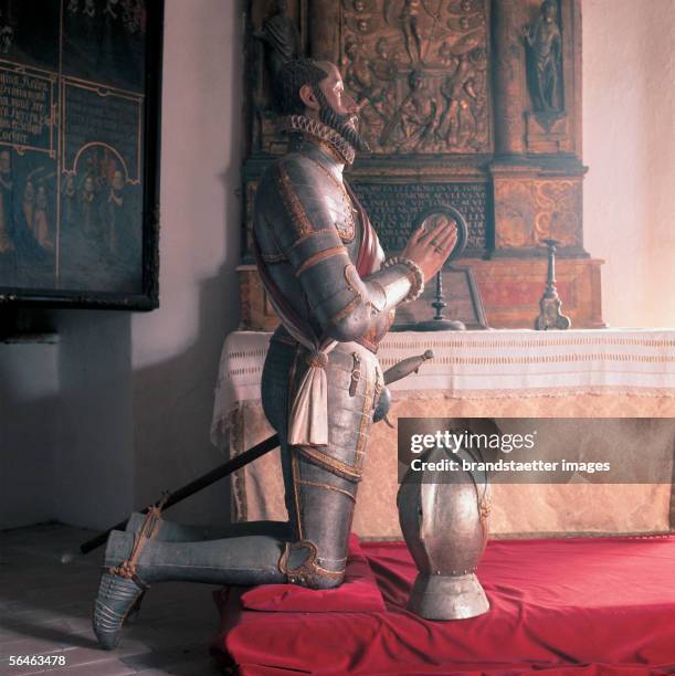 Wood statue of a praying knight from the 16th century in front of a golden bronze altar . Castle Hochosterwitz, Carinthia. Castle museum....