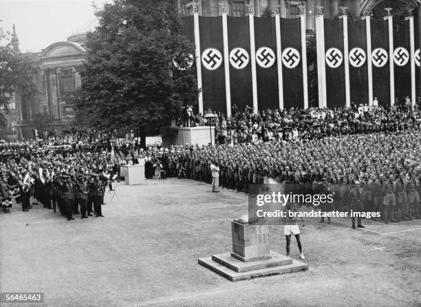 Olympic Summer Games in Berlin in 1936: The finisher lights the olympic fire with his torch in the Lustgasse. 1st of August 1936. Photography. [XI....