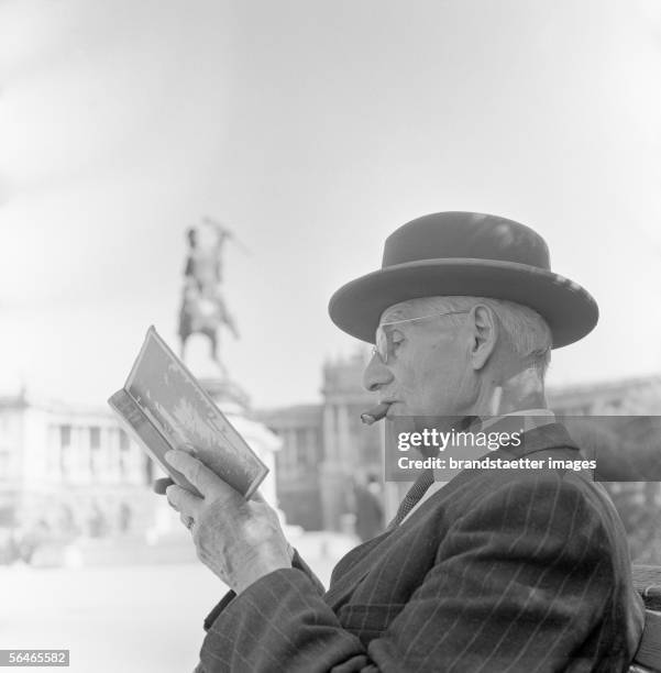 Old Man reading a book on a bench at Heroes Square. Photography. Vienna. Around 1960. [Ein alter Mann liest ein Buch auf einer Parkbank am...