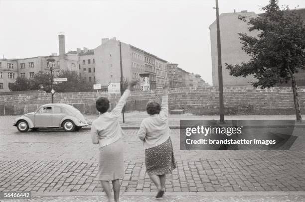 Two women wave to East Berlin. Photography. Germany. 1961/62. [Zwei Frauen winken ueber die Berliner Mauer nach Ost Berlin. Photographie....