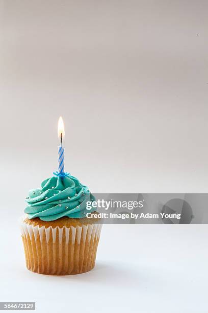 cupcake with blue icing and one candle - cupcake imagens e fotografias de stock