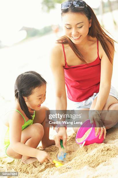 mother with one child on beach, playing with sand - swimwear singlet stock pictures, royalty-free photos & images