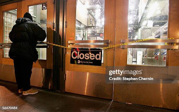 Metropolitan Transit Authority worker strings a yellow chain with a closed sign across the doors of the 72nd street subway station on December 20,...