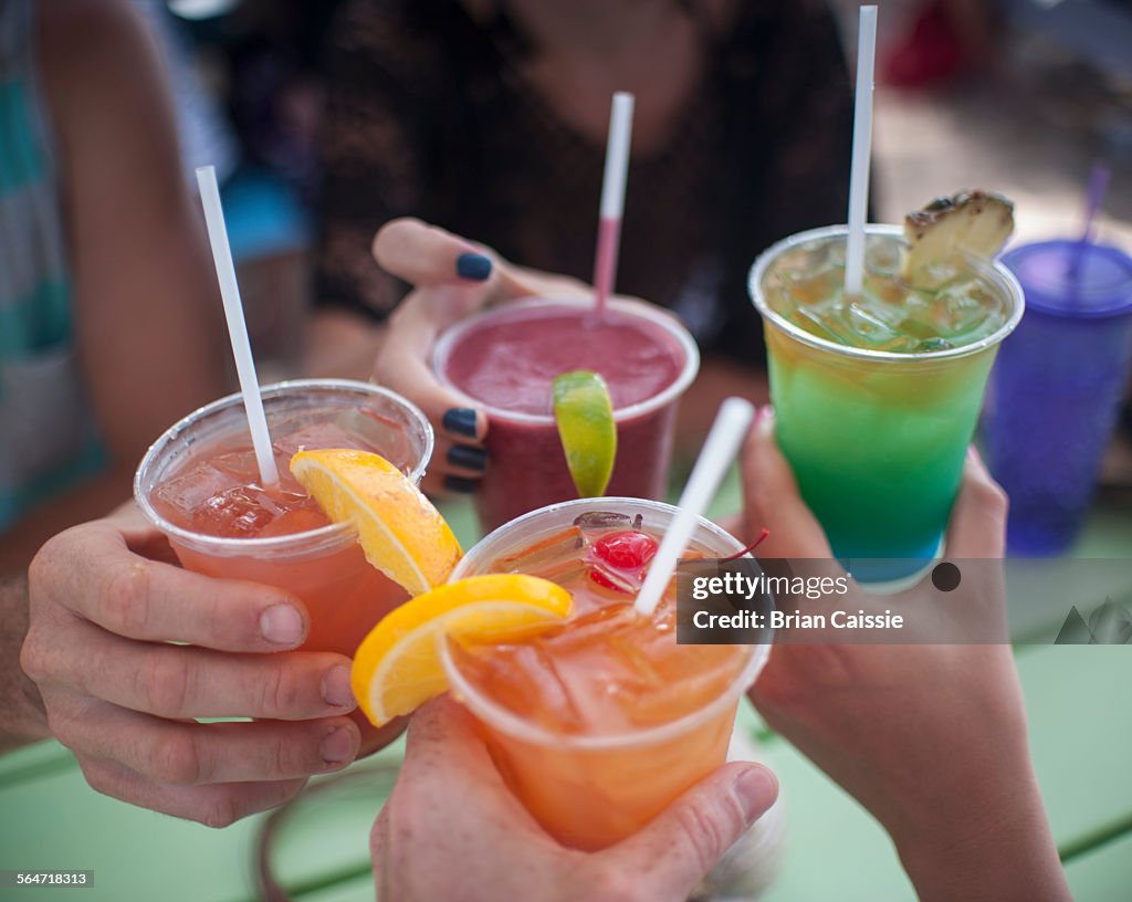 Cropped image of people holding drinks outdoors