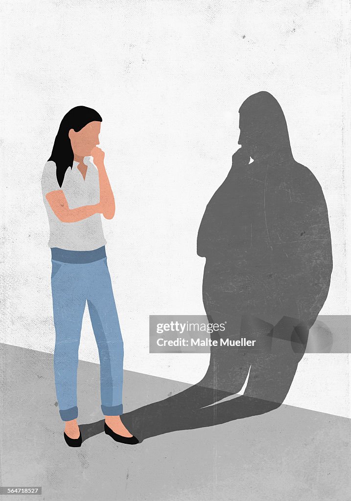 Illustrative image of woman looking at her fat shadow on wall representing worry for obesity