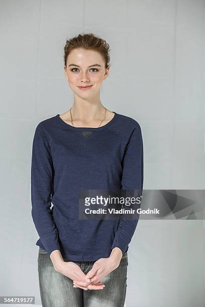 portrait of confident woman standing with hands clasped against white background - three quarter length stockfoto's en -beelden