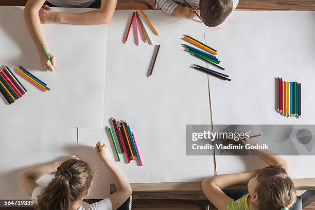 high angle view of children drawing on papers at table - colored pencil foto e immagini stock
