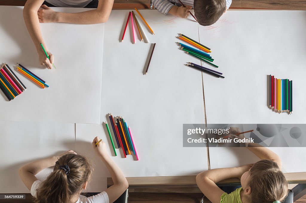 High angle view of children drawing on papers at table