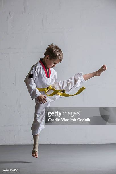 Karate boy kicking in air against white wall