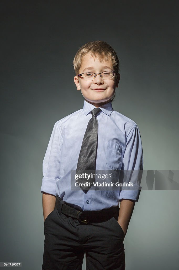 Portrait of well-dressed boy standing against gray background