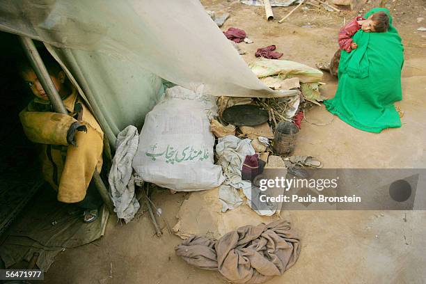 Pakistani children stand by their families temporary shelter after their home was destroyed by the earthquake at a tent camp December 20, 2005 in...