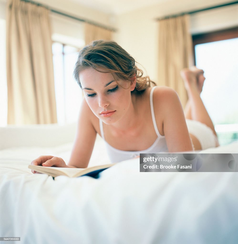 Young Woman Lying on Bed Reading