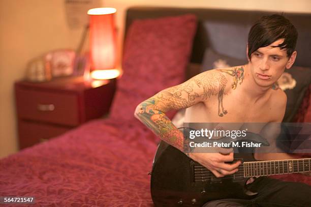 tattooed man playing guitar in bedroom - body art stock pictures, royalty-free photos & images